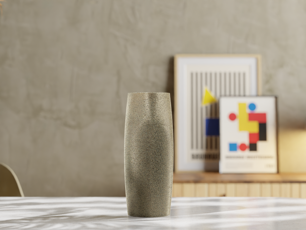 Schmale Vase mit feiner Struktur auf einem hellen Tisch, im Hintergrund gerahmte Grafiken